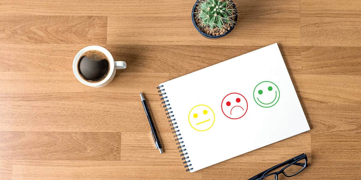 Notebook on desk with drawing of happy, sad and neutral face